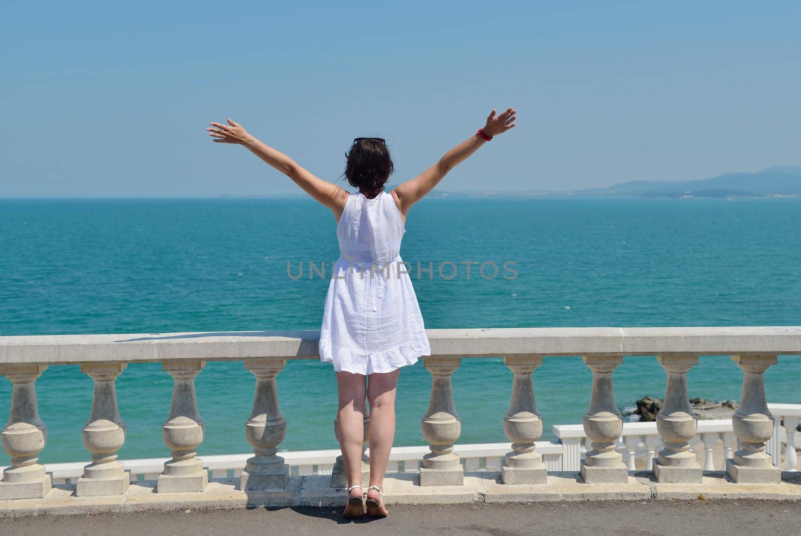 Happy  young woman with spreading arms, blue sky with clouds in background  - copyspace