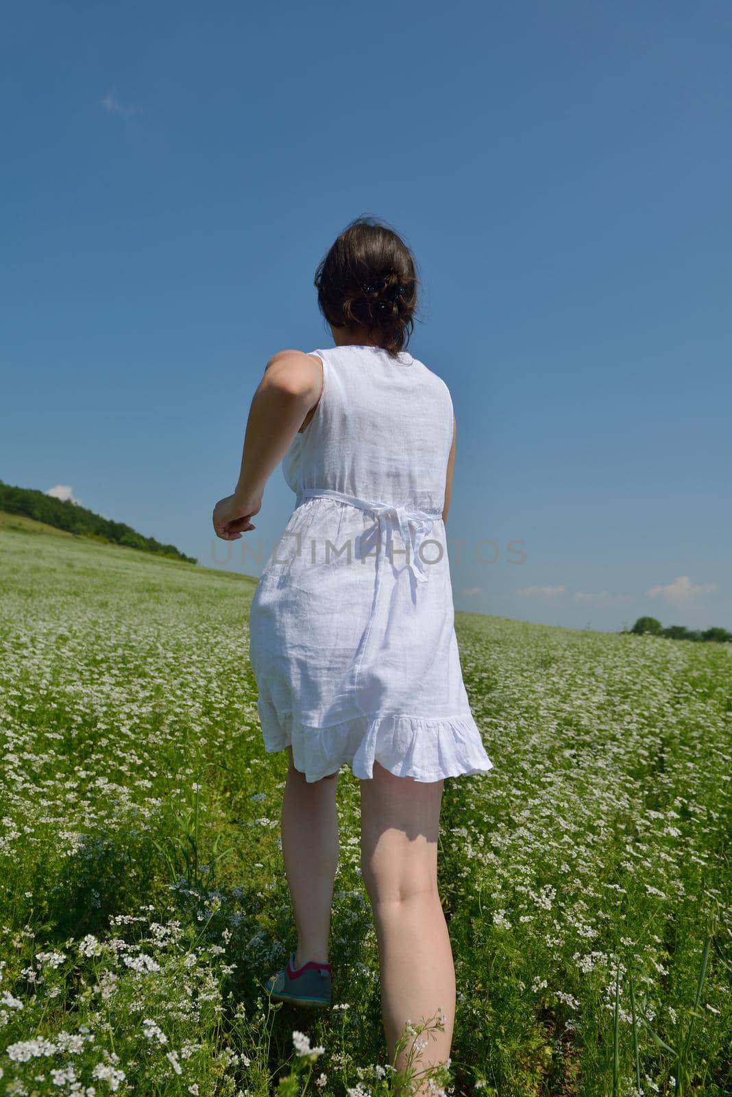 Young happy woman in green field with blue sky in background