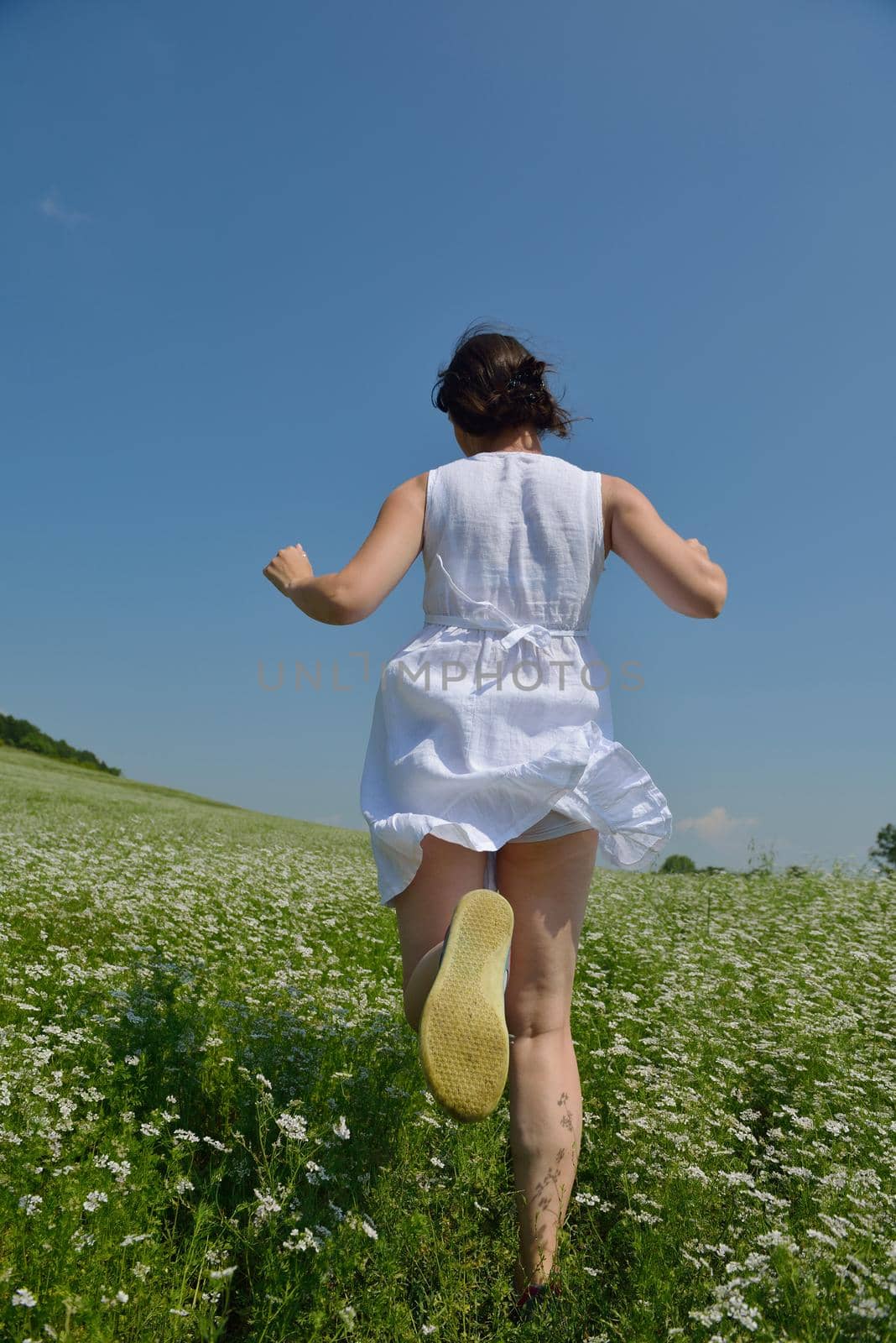 Young happy woman in green field with blue sky in background