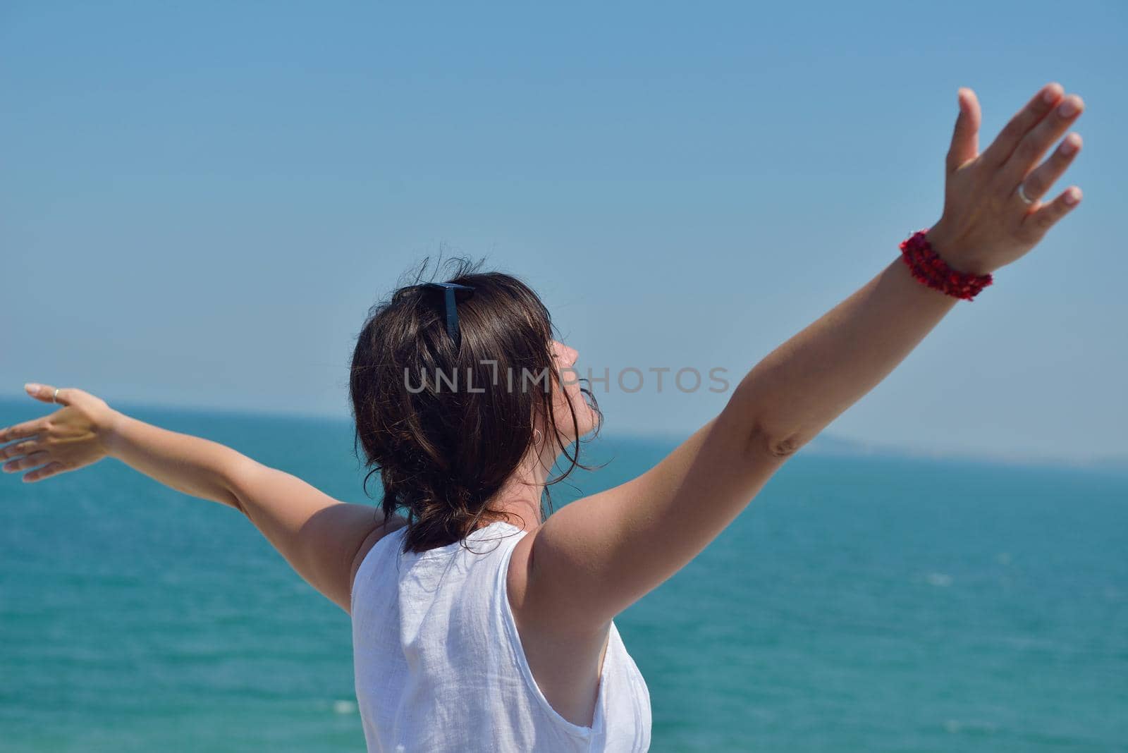 Happy  young woman with spreading arms, blue sky with clouds in background  - copyspace