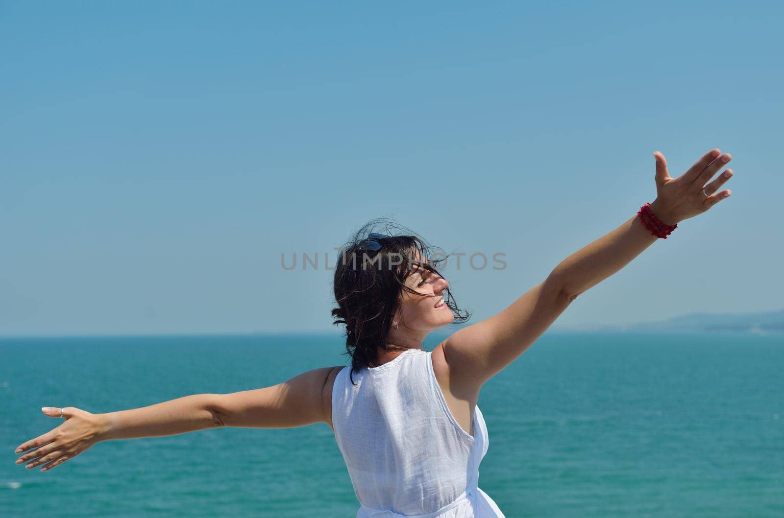 Happy  young woman with spreading arms, blue sky with clouds in background  - copyspace