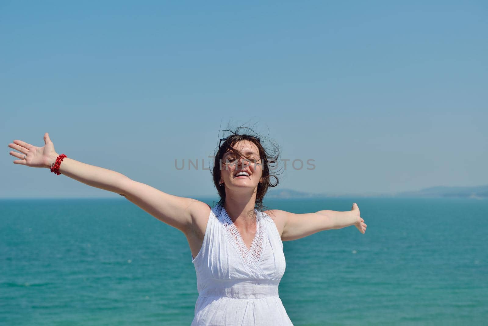 Happy  young woman with spreading arms, blue sky with clouds in background  - copyspace