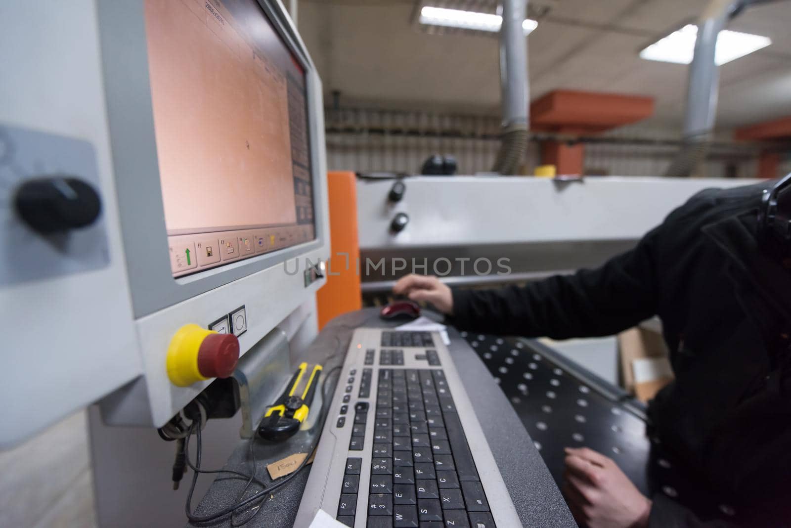 two young carpenters calculating and programming a cnc wood working machine in workshop. wood workers preparing a computer program for CNC machine at big modern carpentry