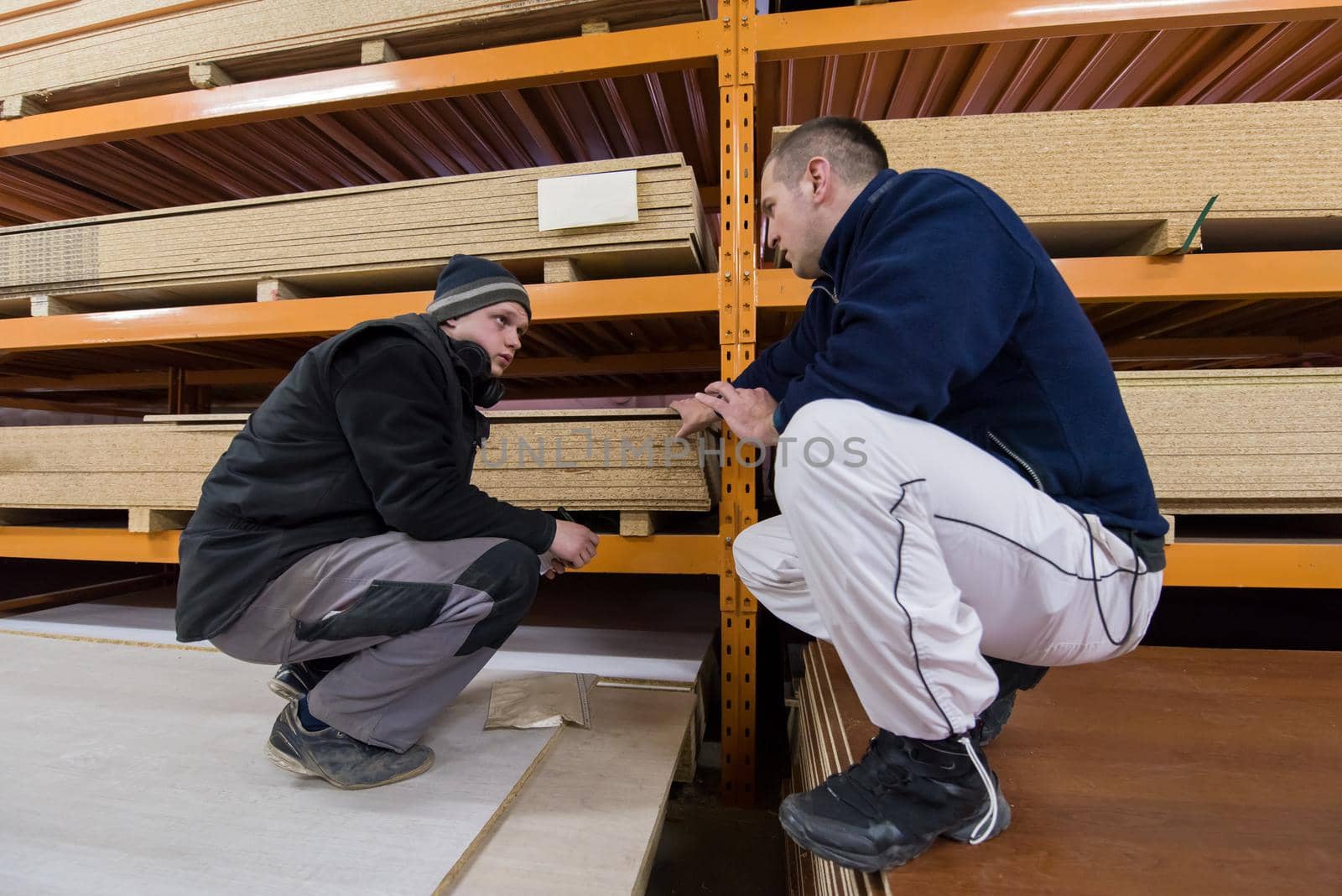 two young carpenters writing new prices while working together in big modern carpentry High quality wood concept