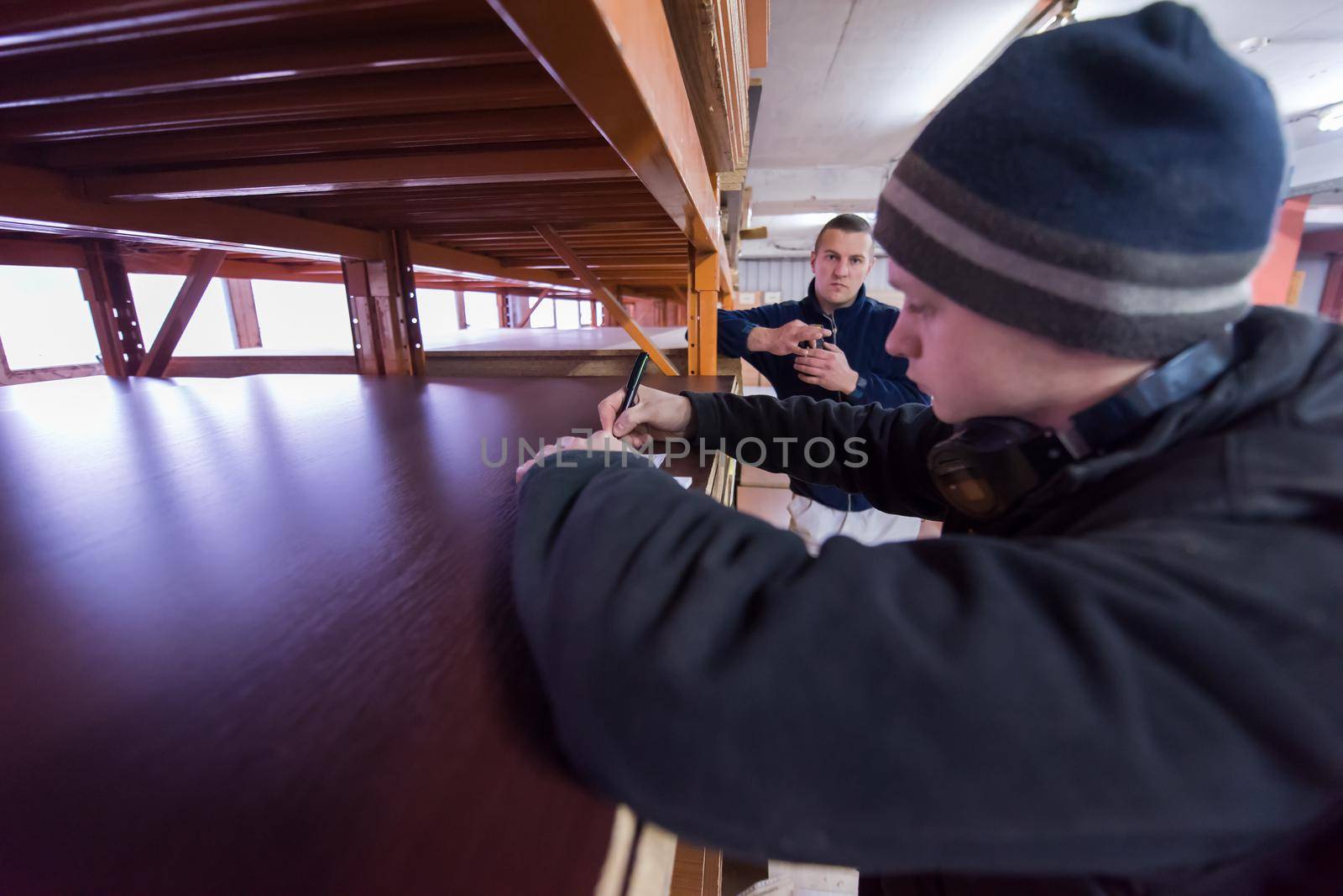 young man carpenter using pen while writing a receipt  in big modern carpentry