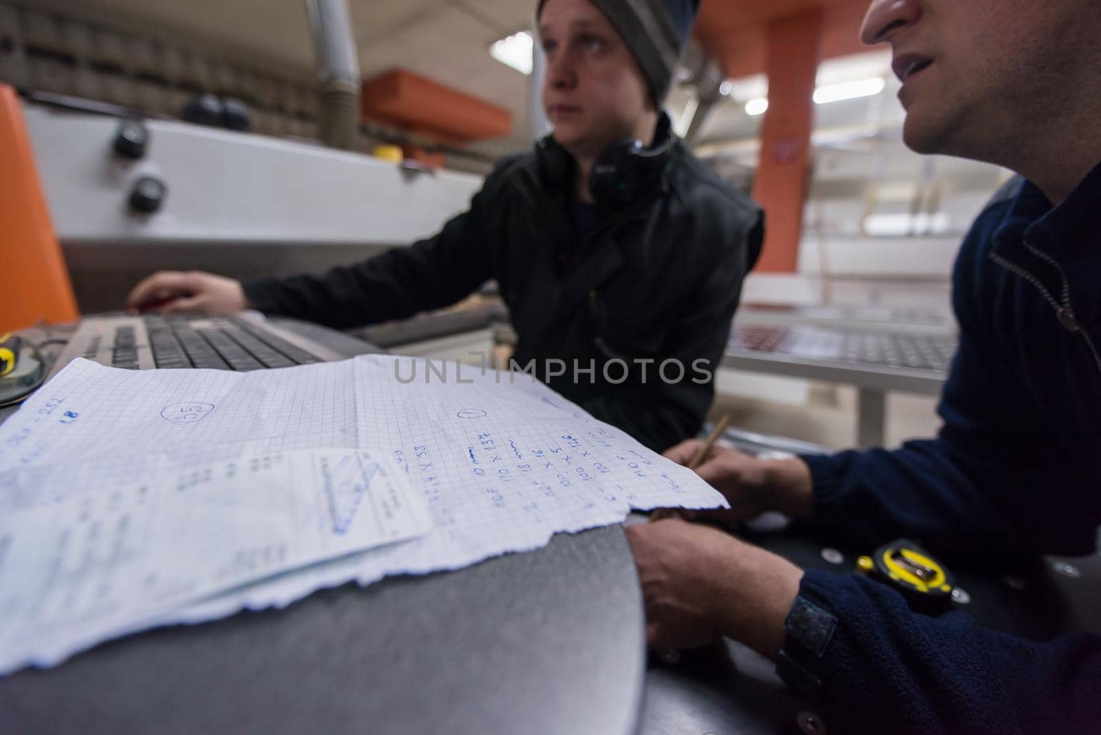 two young carpenters calculating and programming a cnc wood working machine in workshop. wood workers preparing a computer program for CNC machine at big modern carpentry