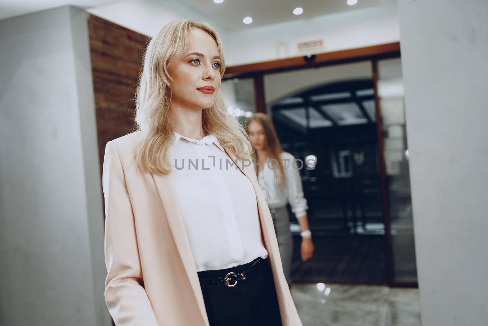 Two young women in formal clothes entering hotel lobby. Business trip concept