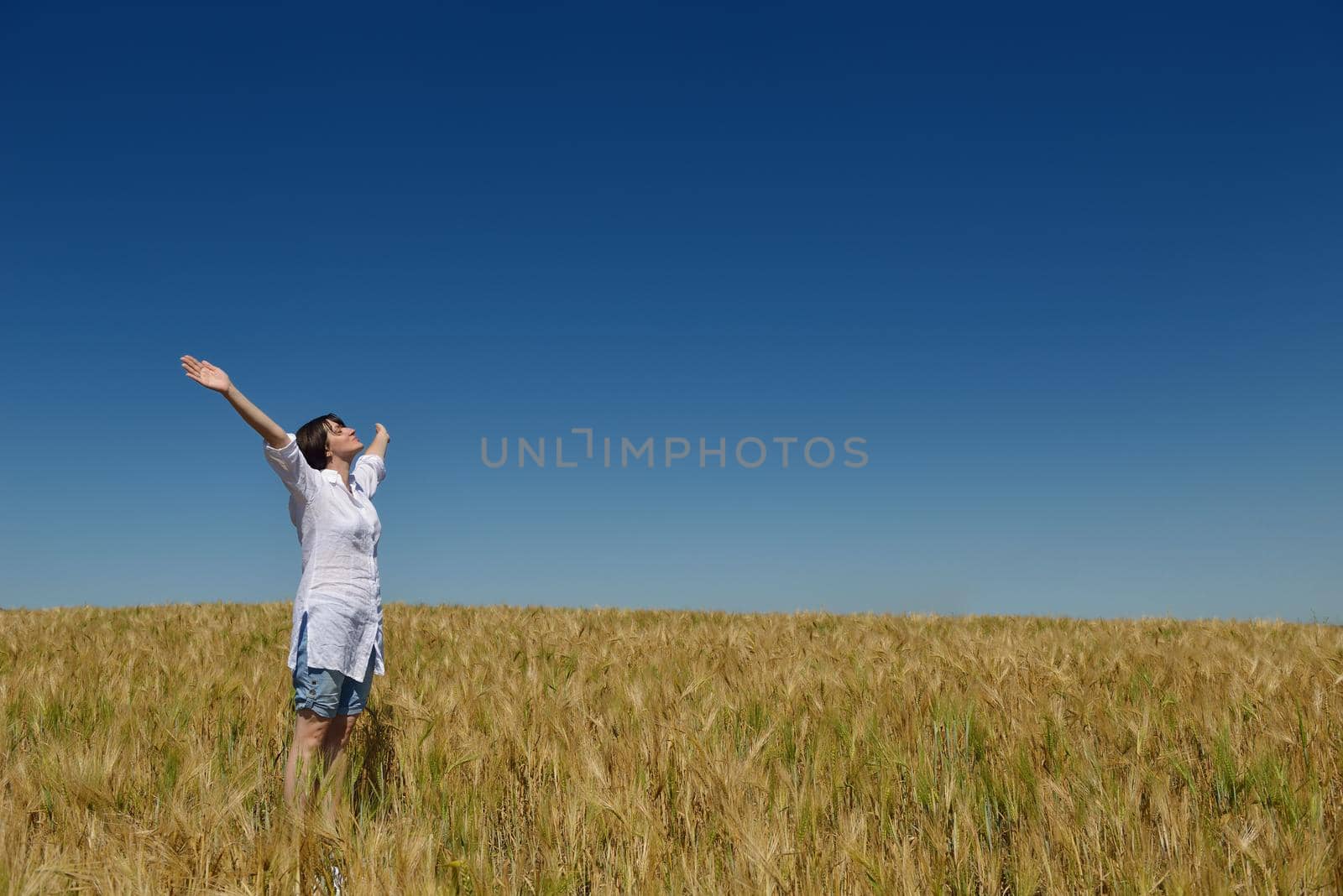 young woman in wheat field at summer by dotshock