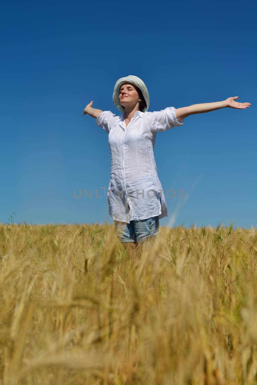 young woman in wheat field at summer by dotshock