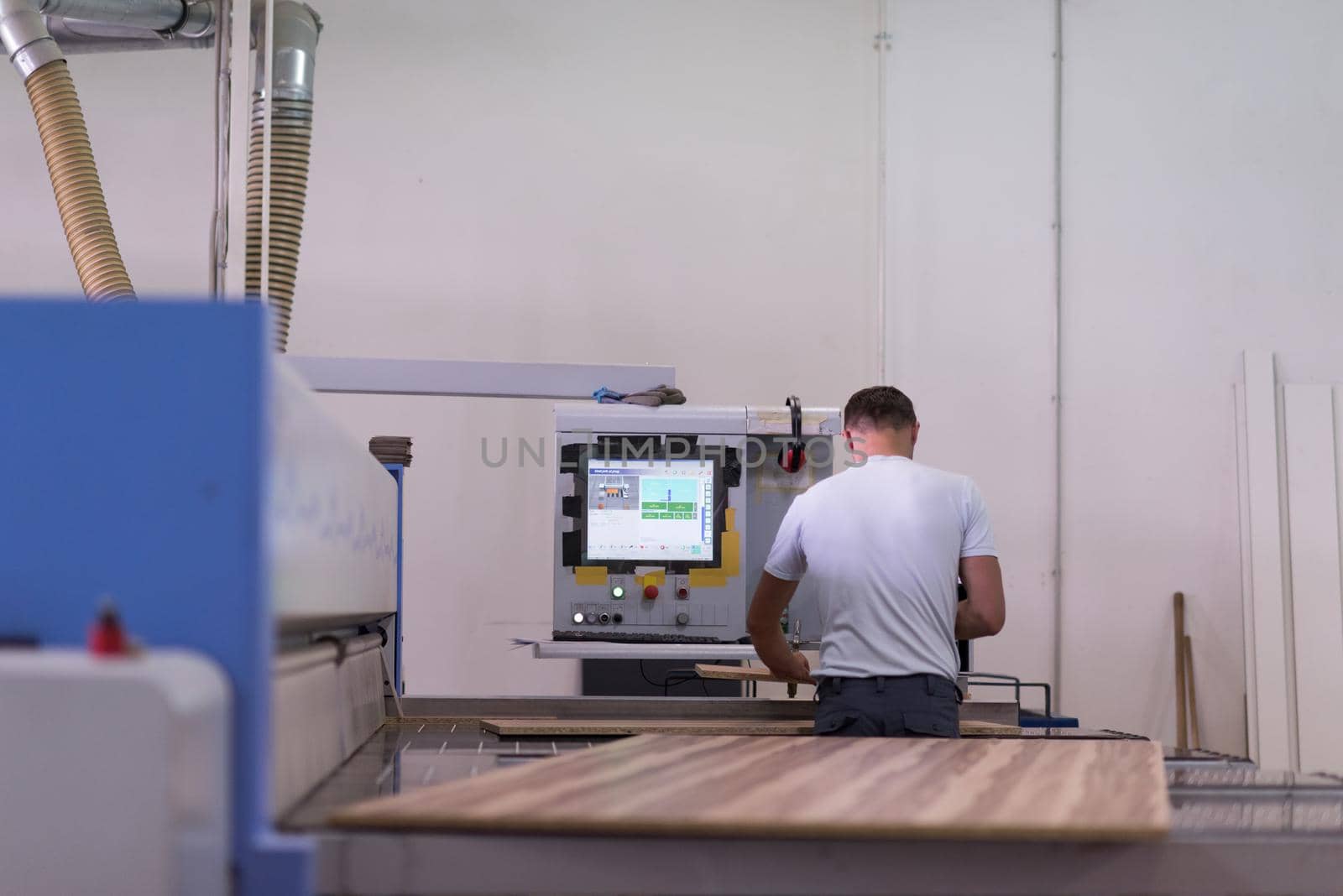 Young worker works in a factory for the production of wooden furniture