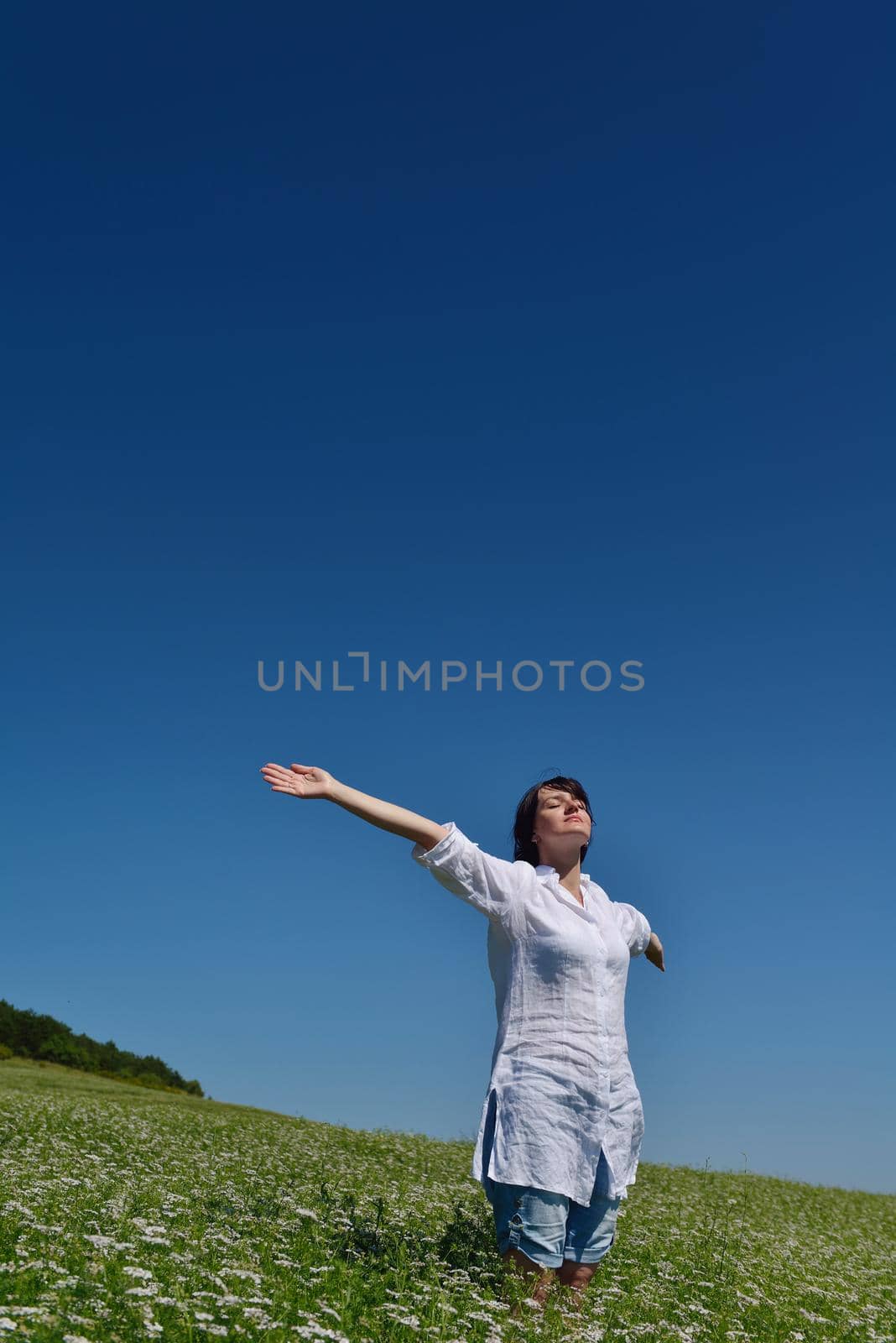 Young happy woman in green field with blue sky in background