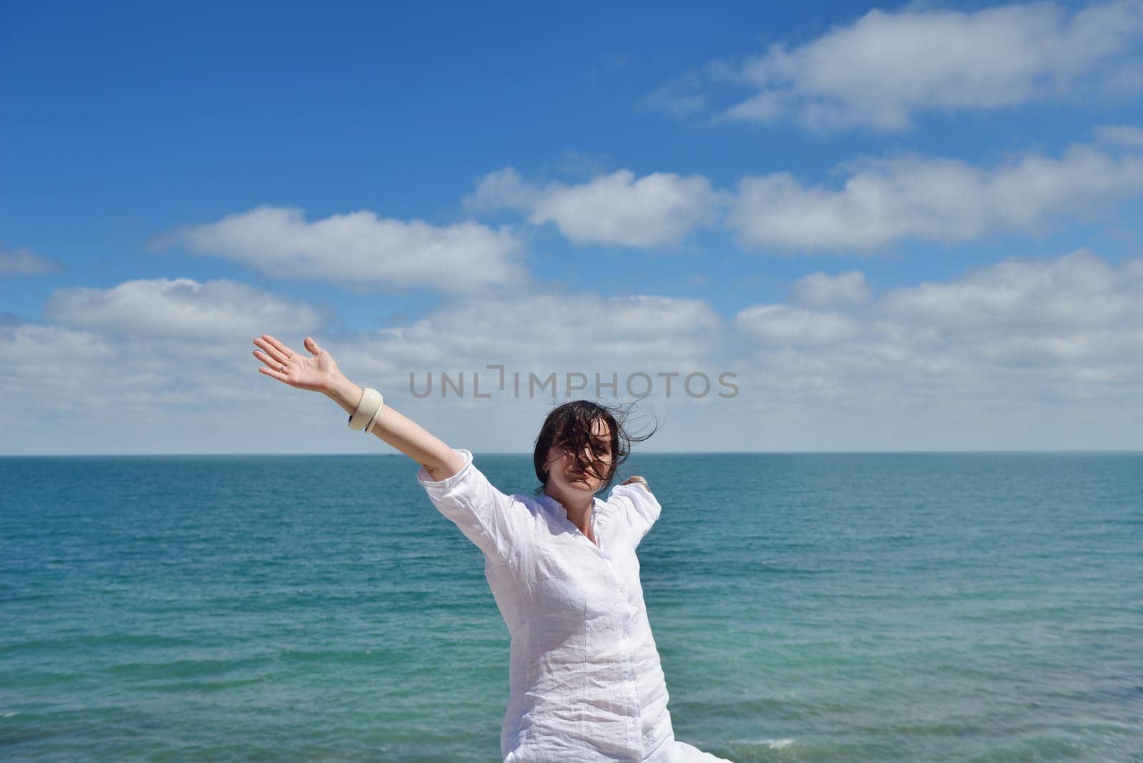 Happy  young woman with spreading arms, blue sky with clouds in background  - copyspace