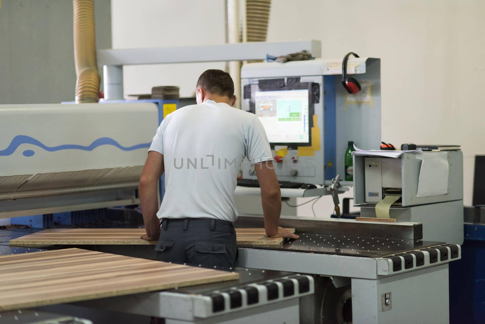 Young worker works in a factory for the production of wooden furniture