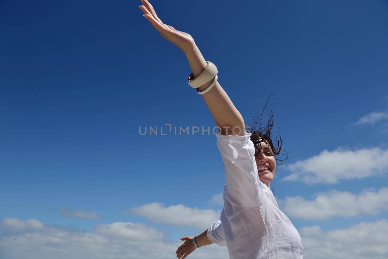 Happy  young woman with spreading arms, blue sky with clouds in background  - copyspace