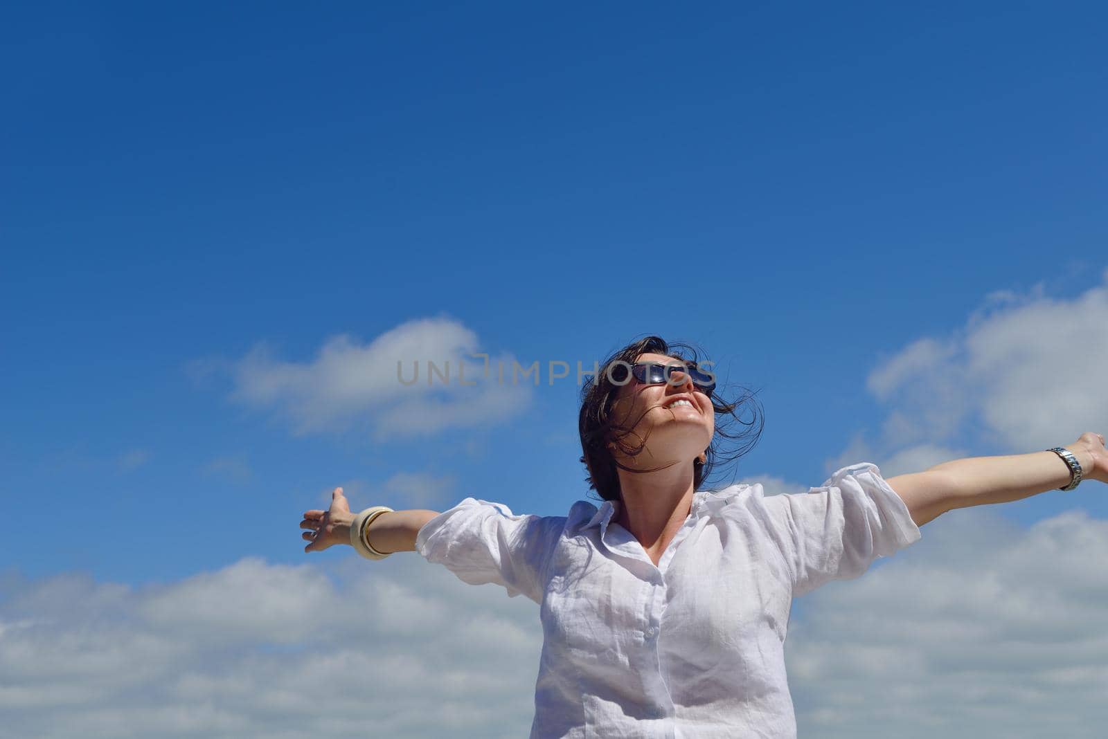 healthy Happy  young woman with spreading arms, blue sky with clouds in background  - copyspace