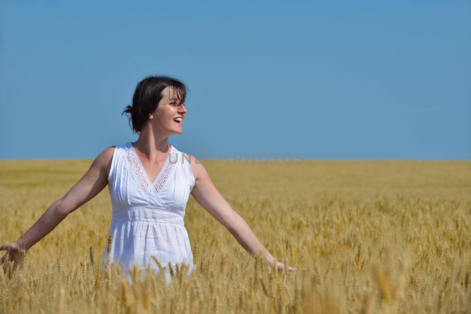 young woman in wheat field at summer by dotshock