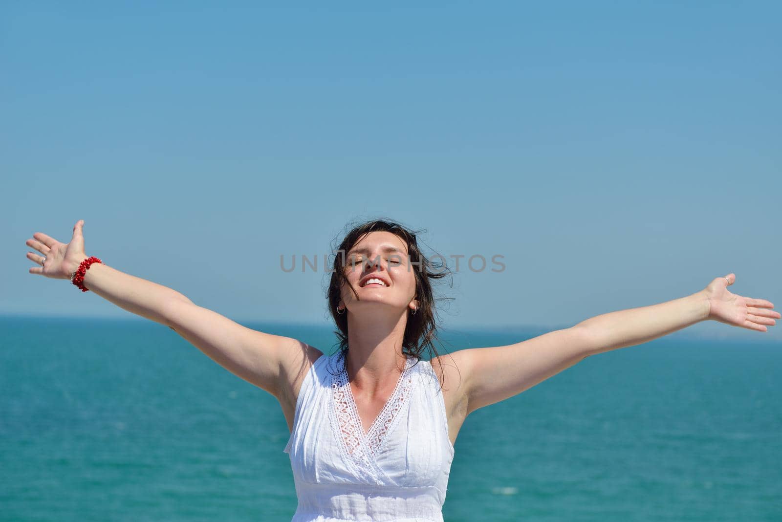 Happy  young woman with spreading arms, blue sky with clouds in background  - copyspace