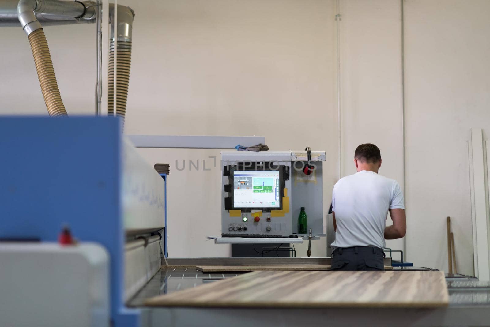 Young worker works in a factory for the production of wooden furniture