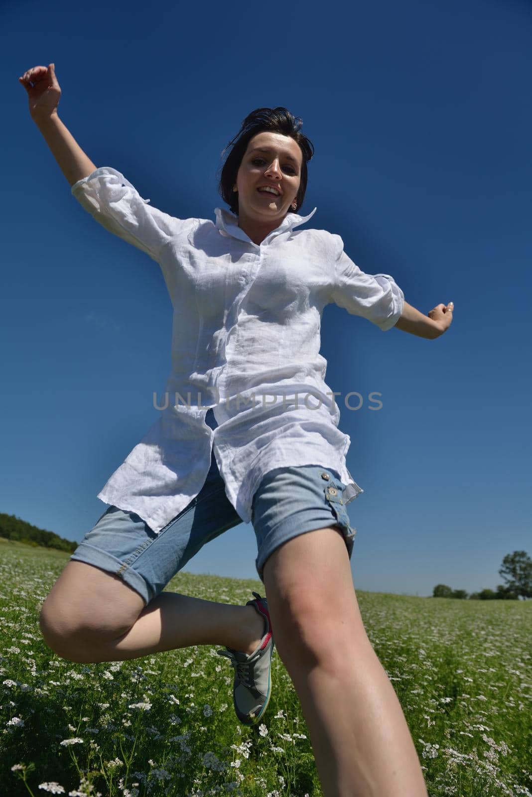 Young happy woman in green field with blue sky in background