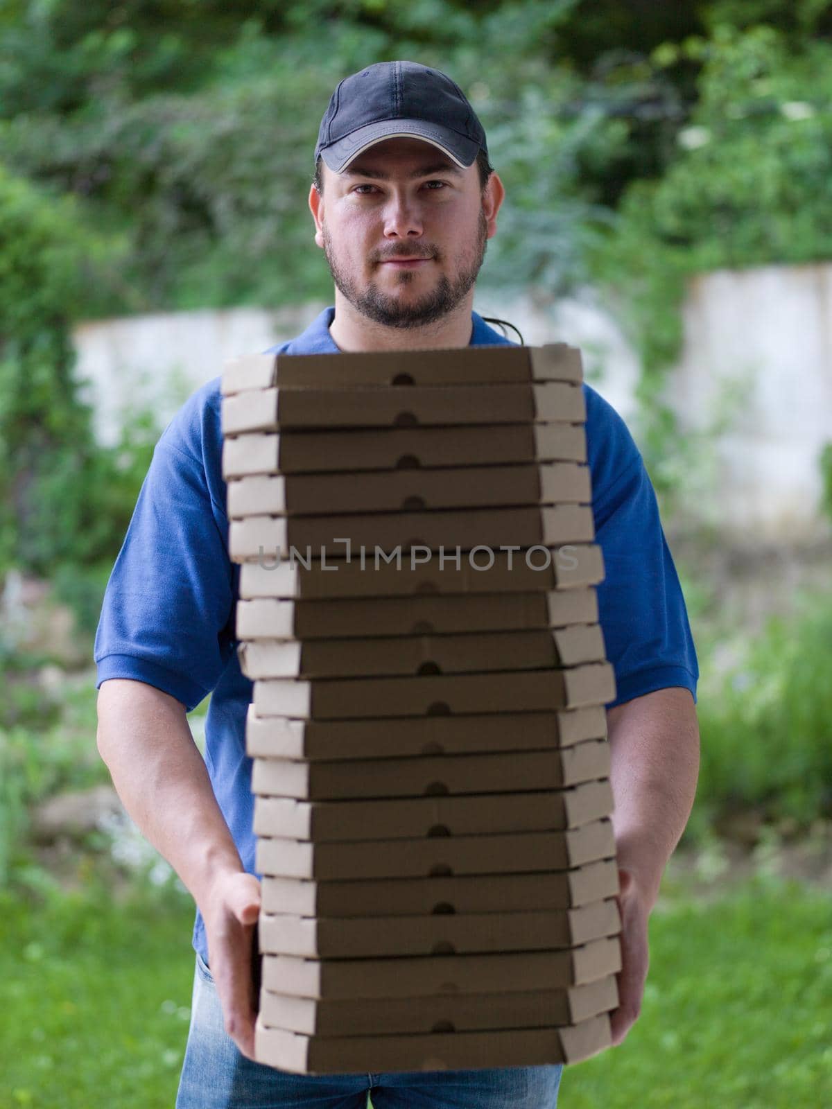 pizza delivery  portrait of a young deliverers with lots of stacked boxes of pizza in hands