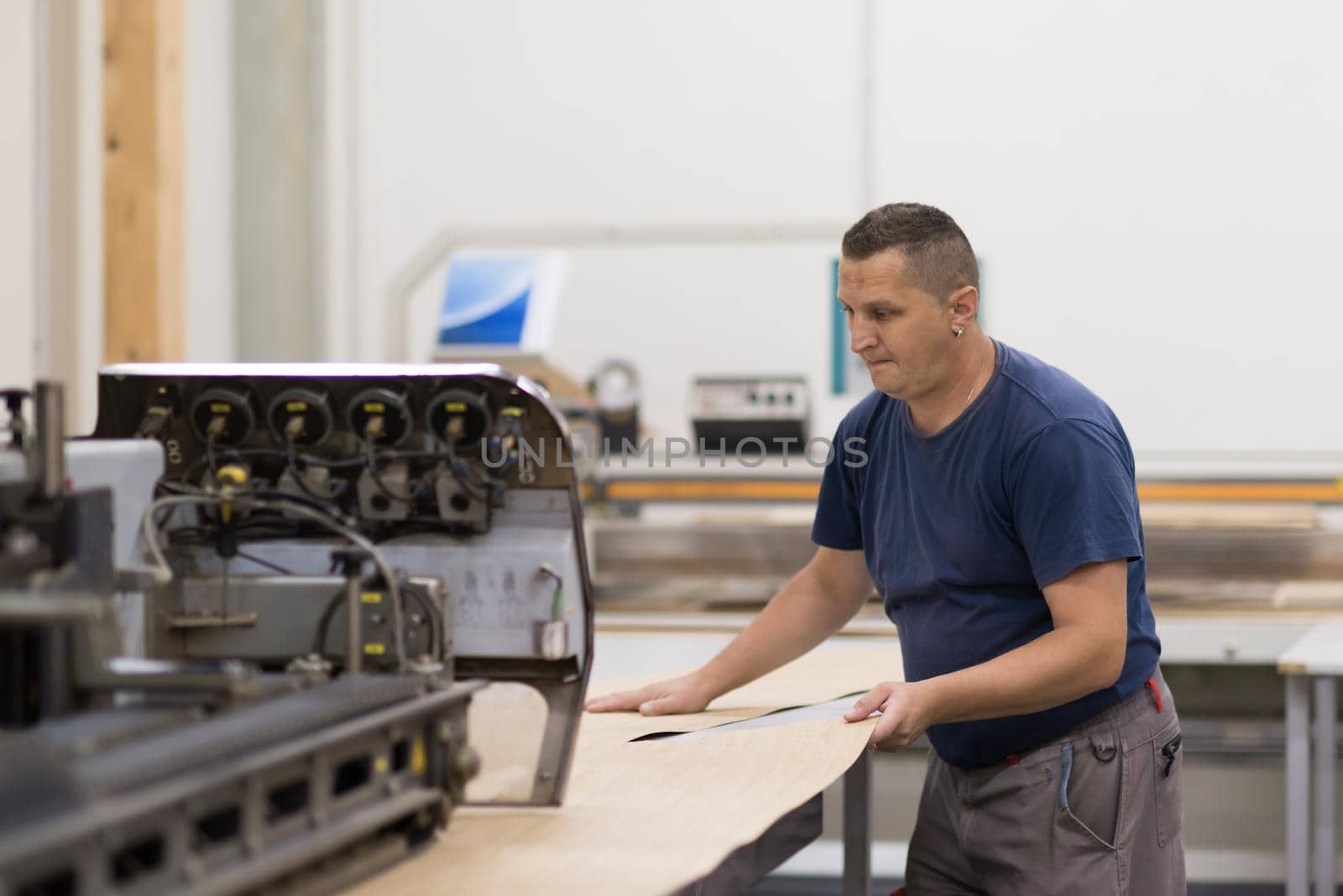 Young worker works in a factory for the production of wooden furniture