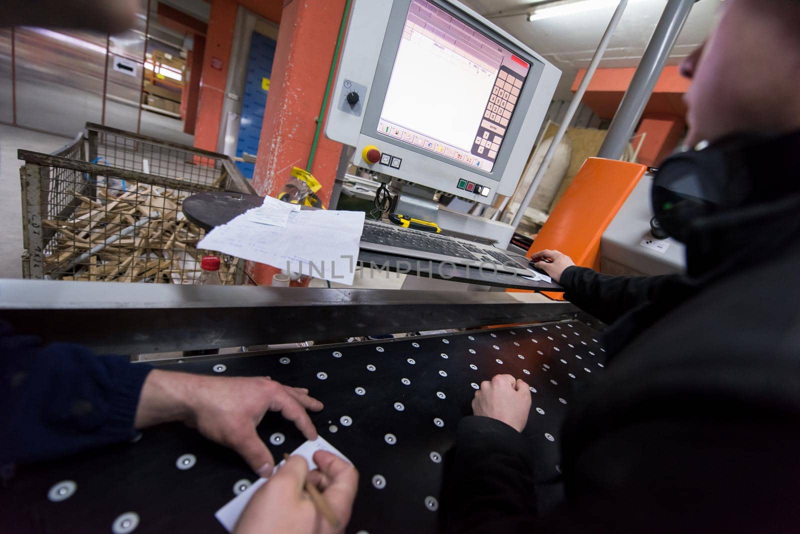 two young carpenters calculating and programming a cnc wood working machine in workshop. wood workers preparing a computer program for CNC machine at big modern carpentry