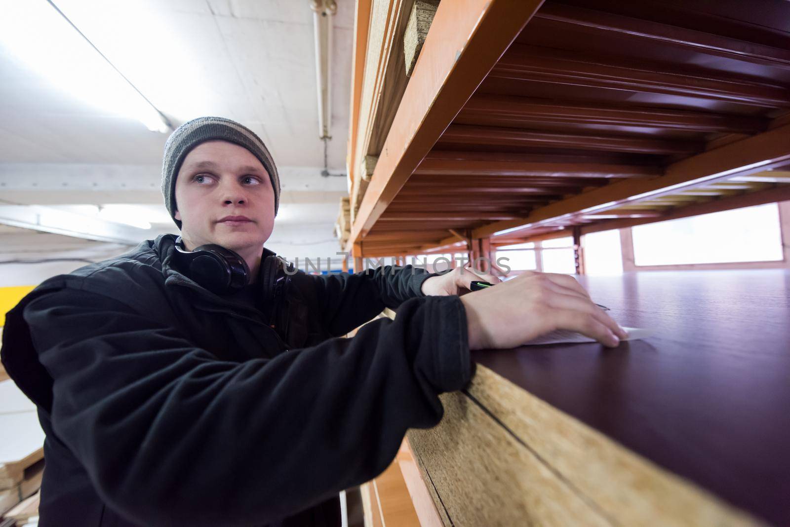 young man carpenter using pen while writing a receipt  in big modern carpentry