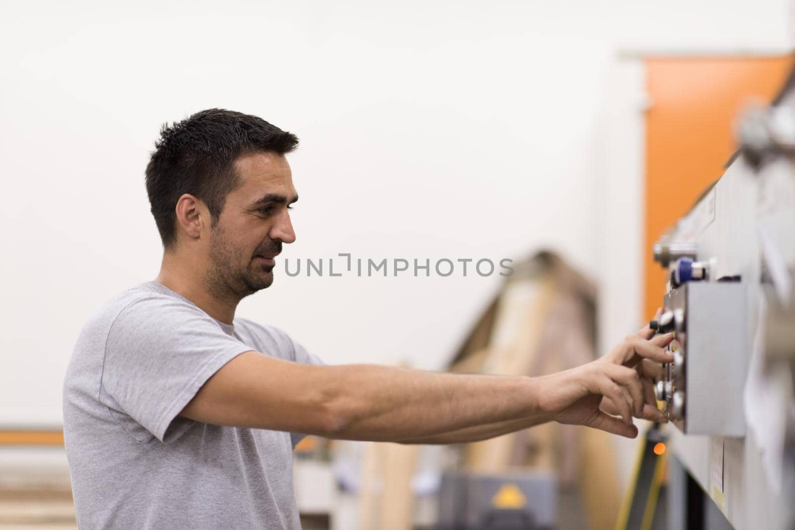 Young worker works in a factory for the production of wooden furniture