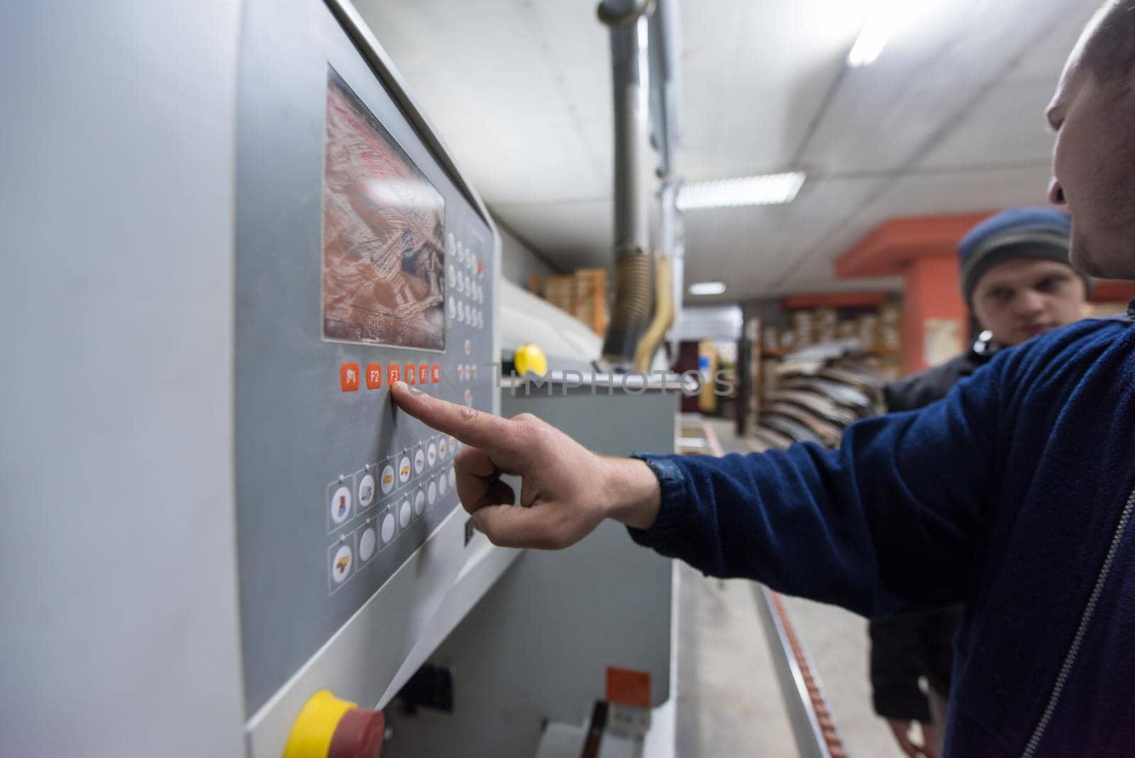 young carpenter calculating and programming a cnc wood working machine in workshop. wood worker preparing a computer program for CNC machine at big modern carpentry