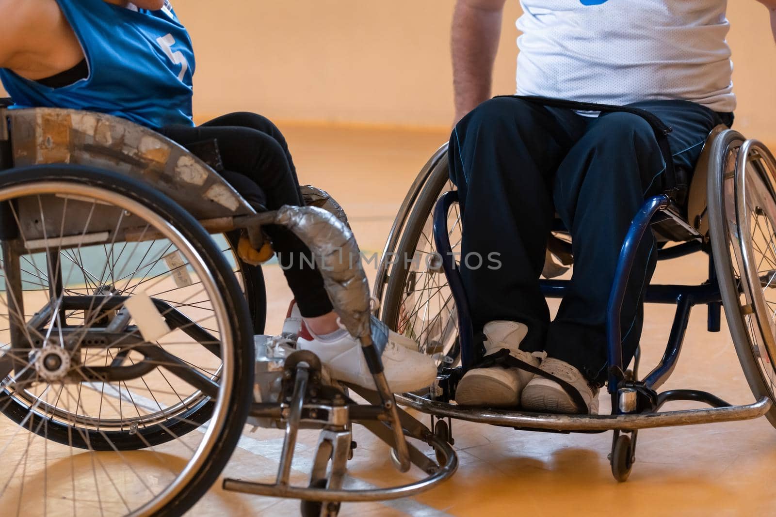 Close up photo of wheelchairs and handicapped war veterans playing basketball on the court. High quality photo