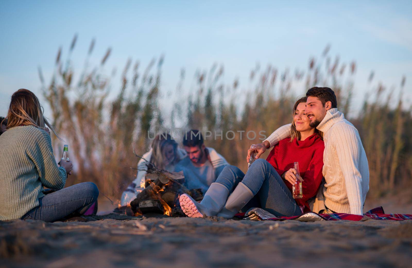 Couple enjoying with friends at sunset on the beach by dotshock