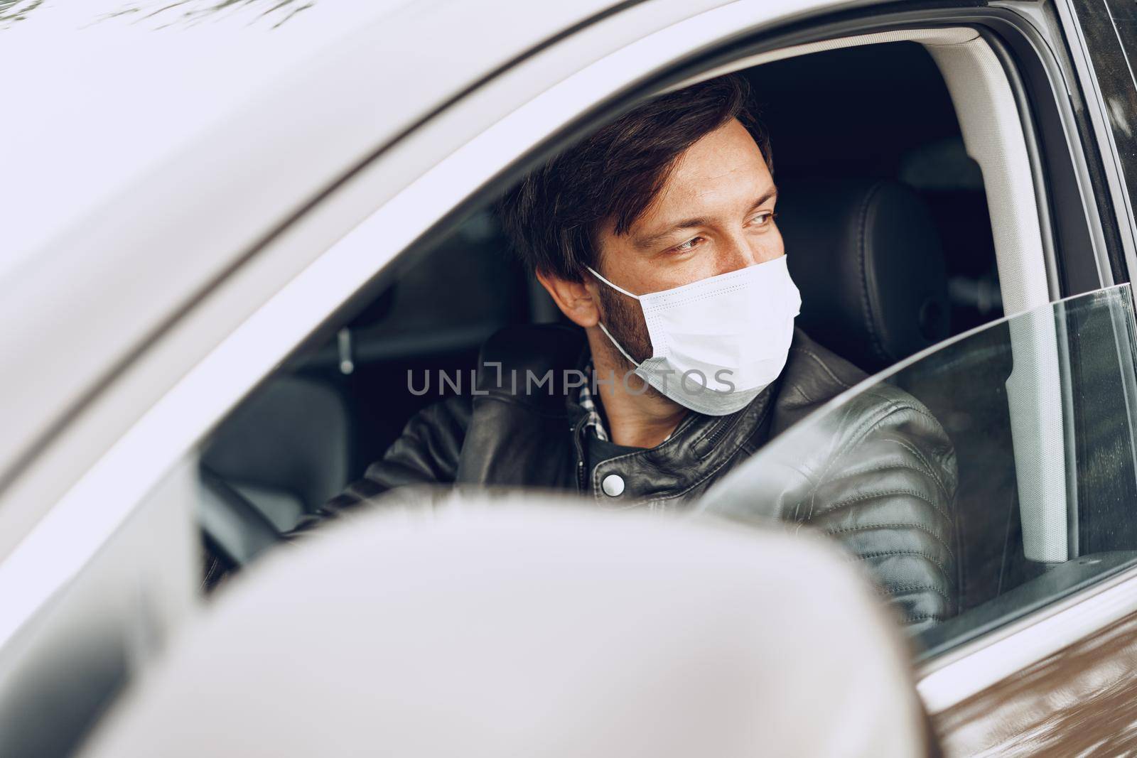 Young man driving car in medical mask, clsoe up