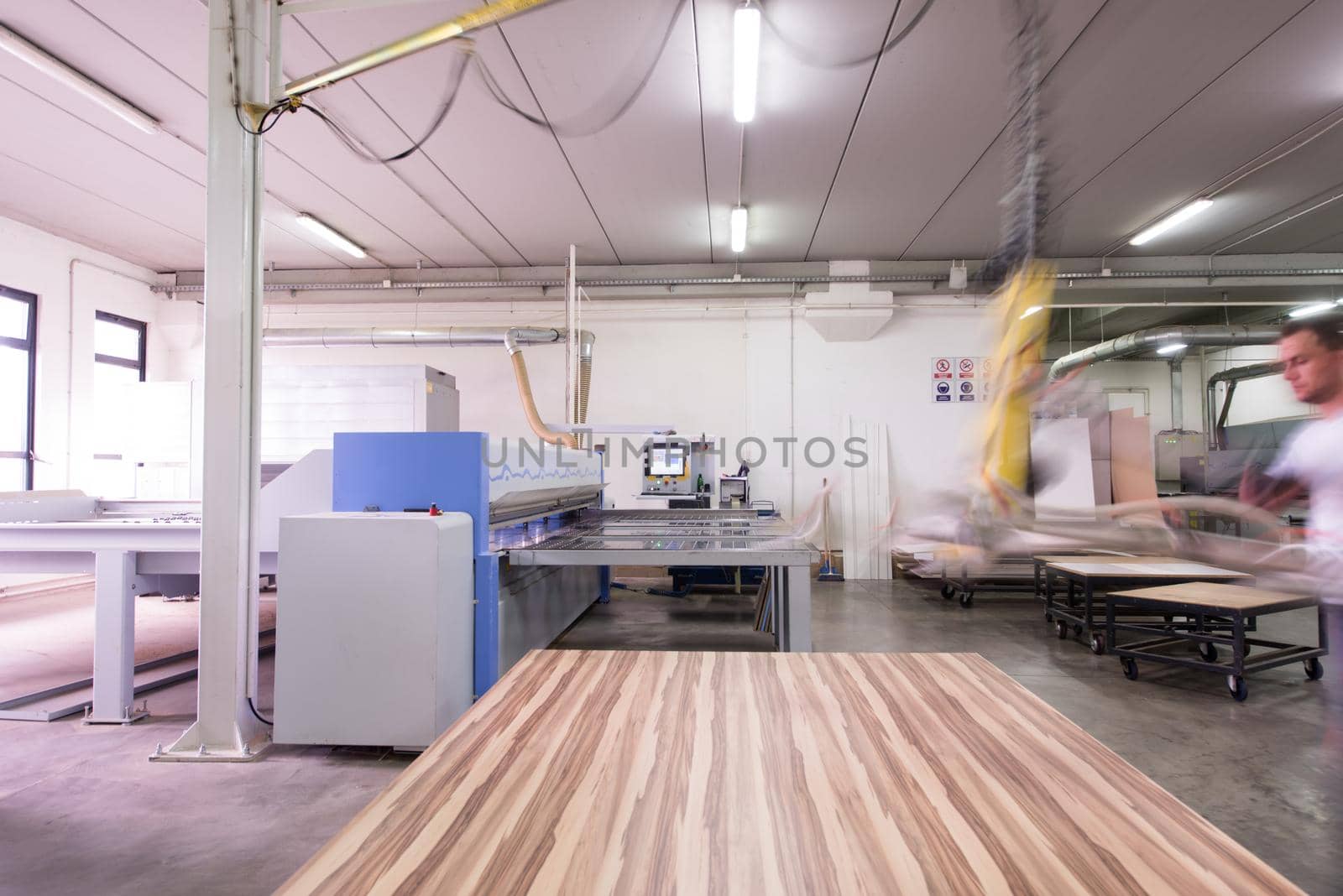 Young worker works in a factory for the production of wooden furniture