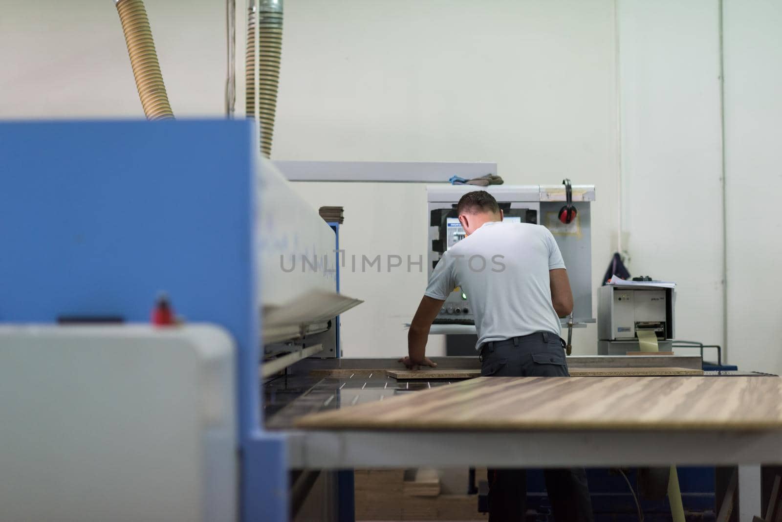 Young worker works in a factory for the production of wooden furniture