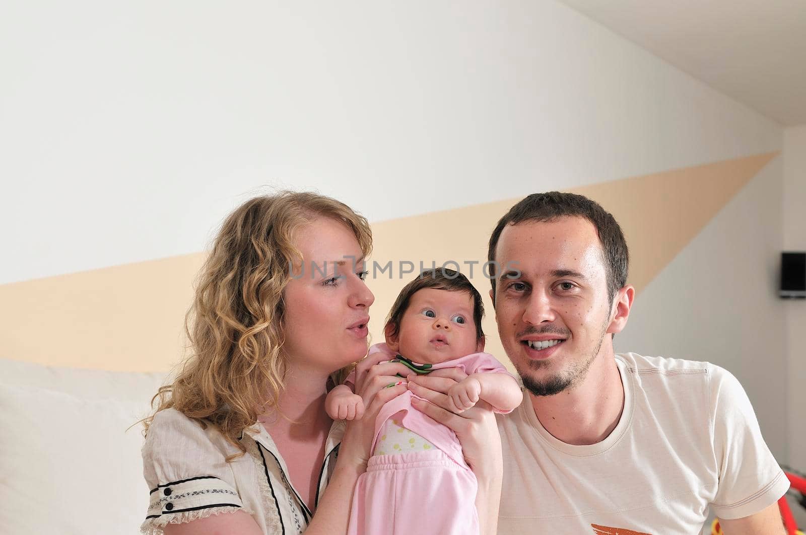 indoor portrait with happy young family and  cute little babby