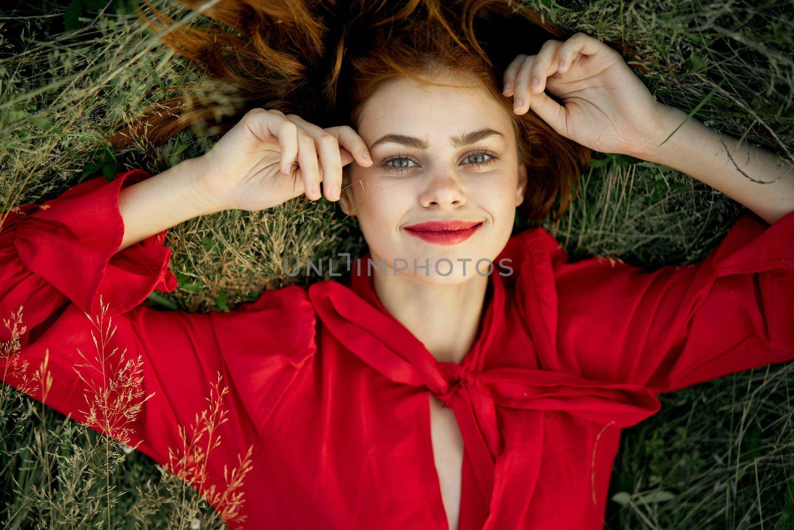 woman in red dress lies on the grass top view freedom. High quality photo