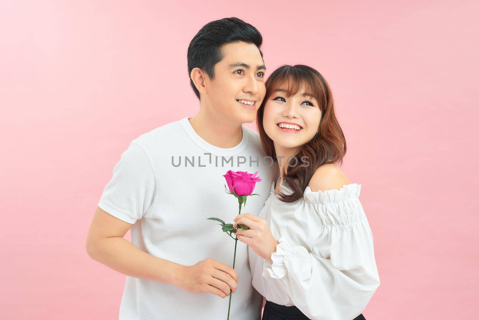 Lovely couple holding flower on pink background by makidotvn