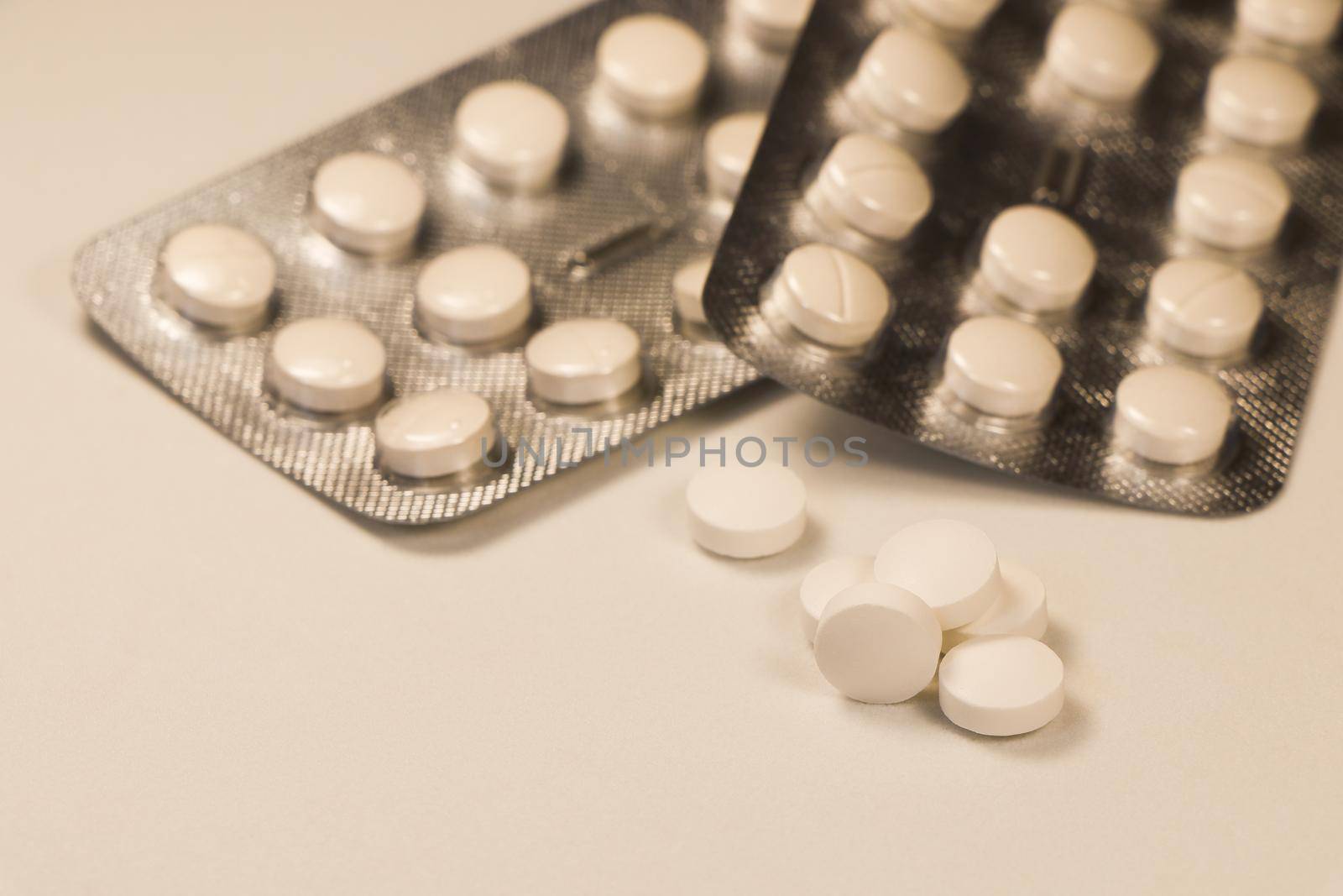 White prescription pills with pill packaging strips close-up abstract on white