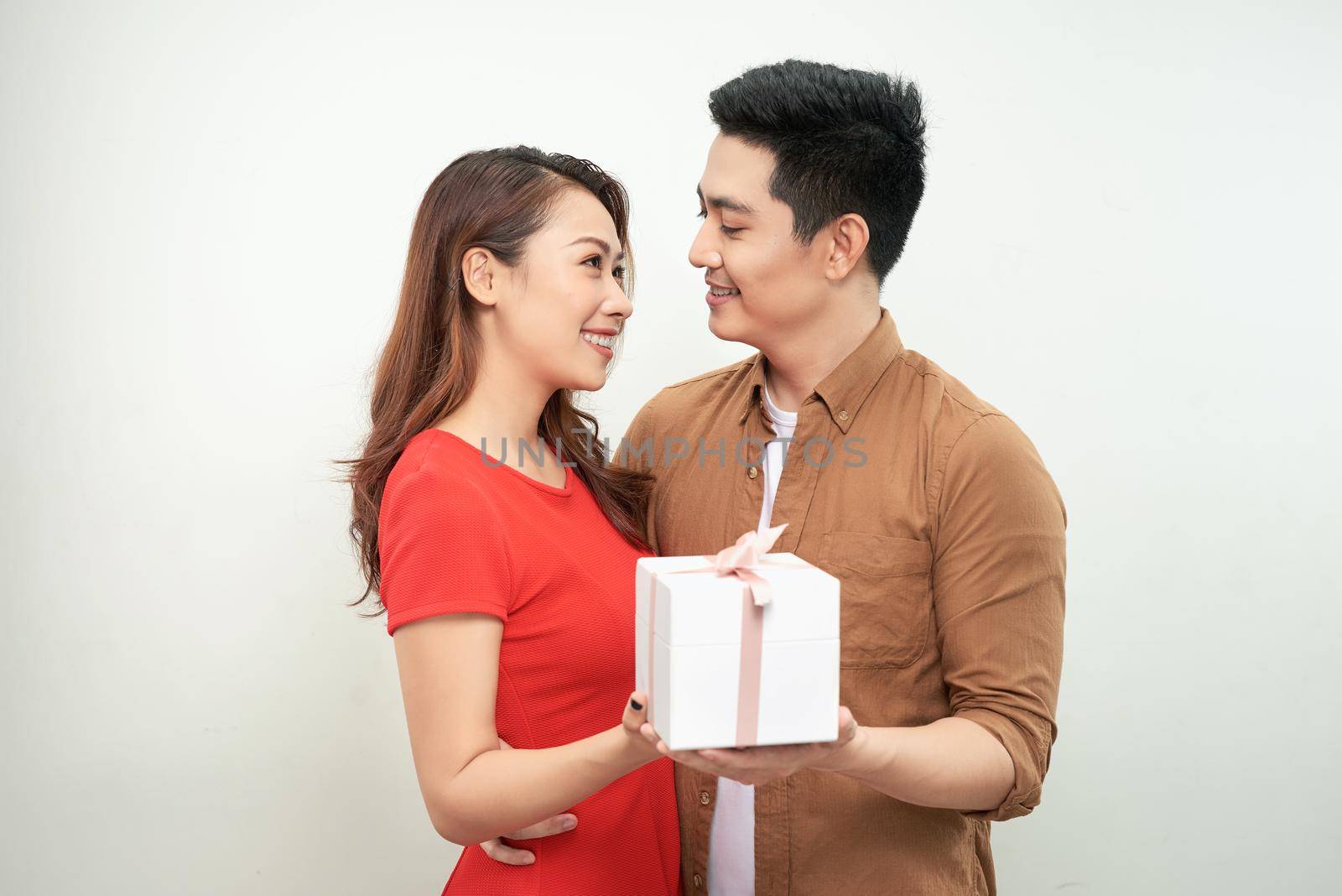 Couple in Valentine Day holding a gift over isolated background hugging by makidotvn