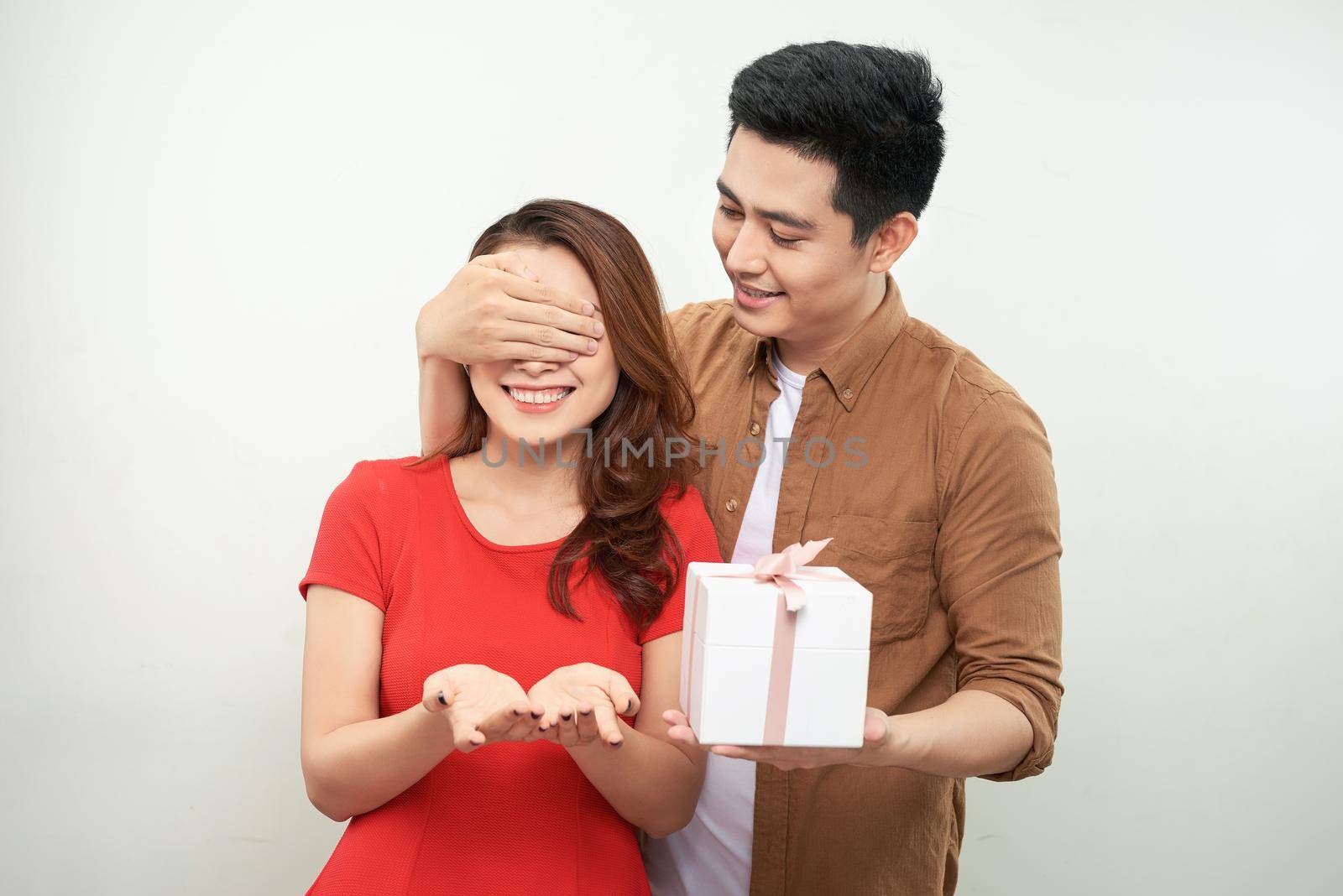 Gift couple holding present closing someone eyes by makidotvn