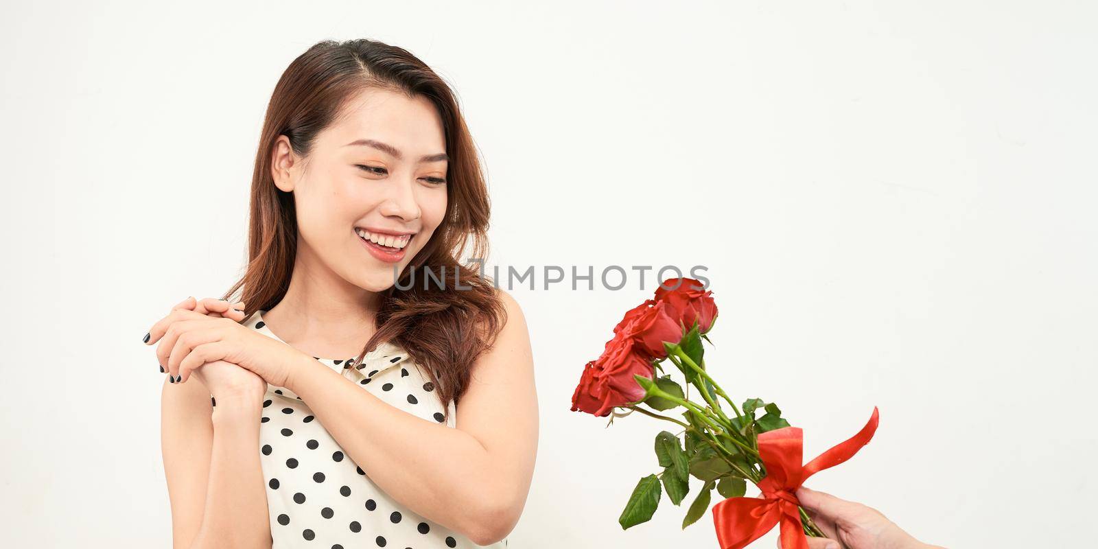 Man giving a bunch of red roses to a surprised woman isolated on white background