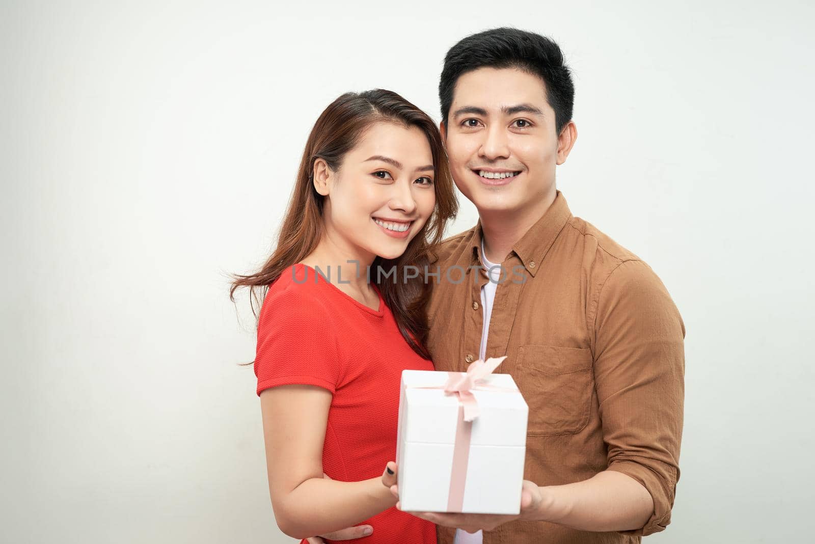 Surprised young couple isolated on white background. Valentine's Day Women's Day, birthday, holiday concept. Hold red present box with gift ribbon bow