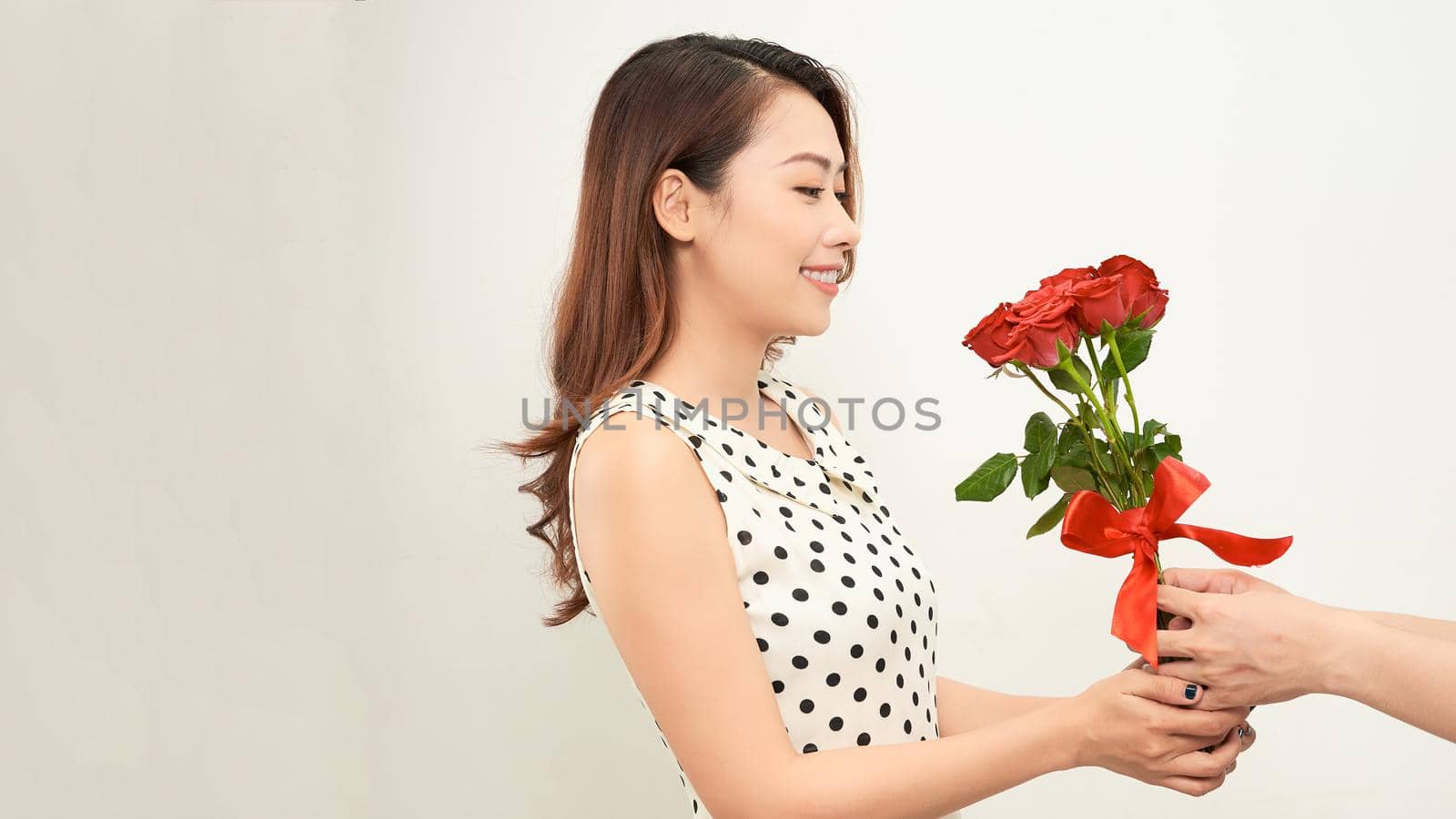 Man giving a bunch of red roses to a surprised woman isolated on white background by makidotvn