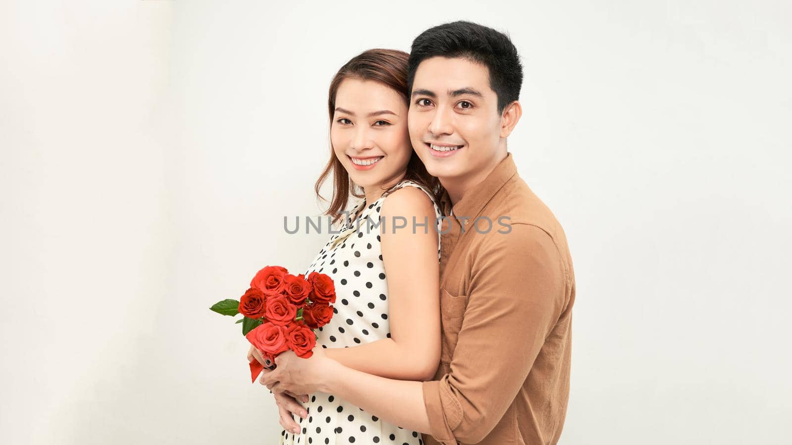 Young beautiful asian couple with flowers isolated on white