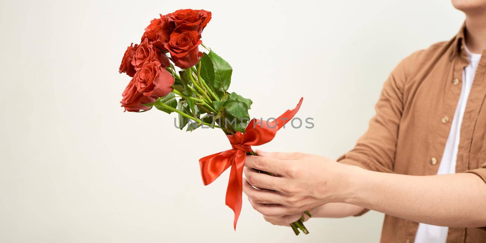 Smiling Asian man holding bunch of roses. Young man looking at camera. Flowers and gift concept.  by makidotvn