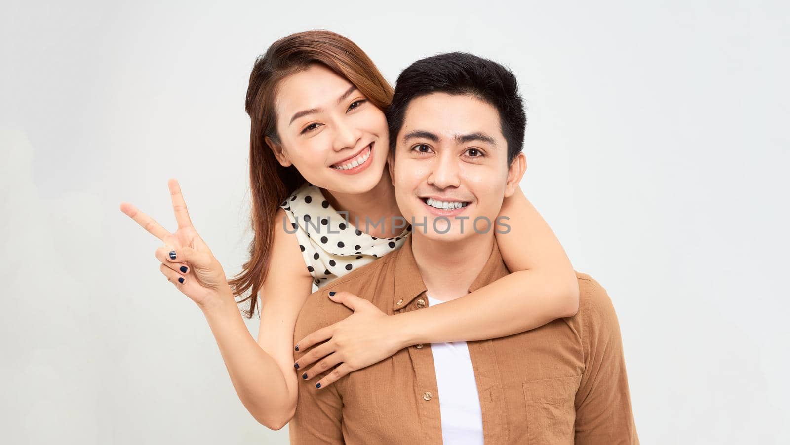 Love forever. Young asian handsome boyfriend is piggybacking his cute lover, wearing casual clothes, on white background