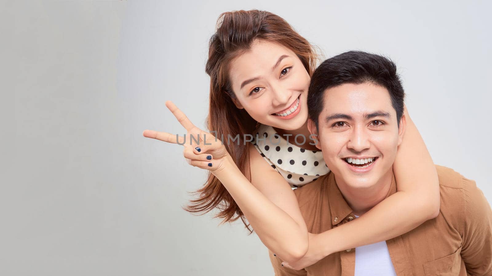 Happy man giving his girlfriend piggy back on white background