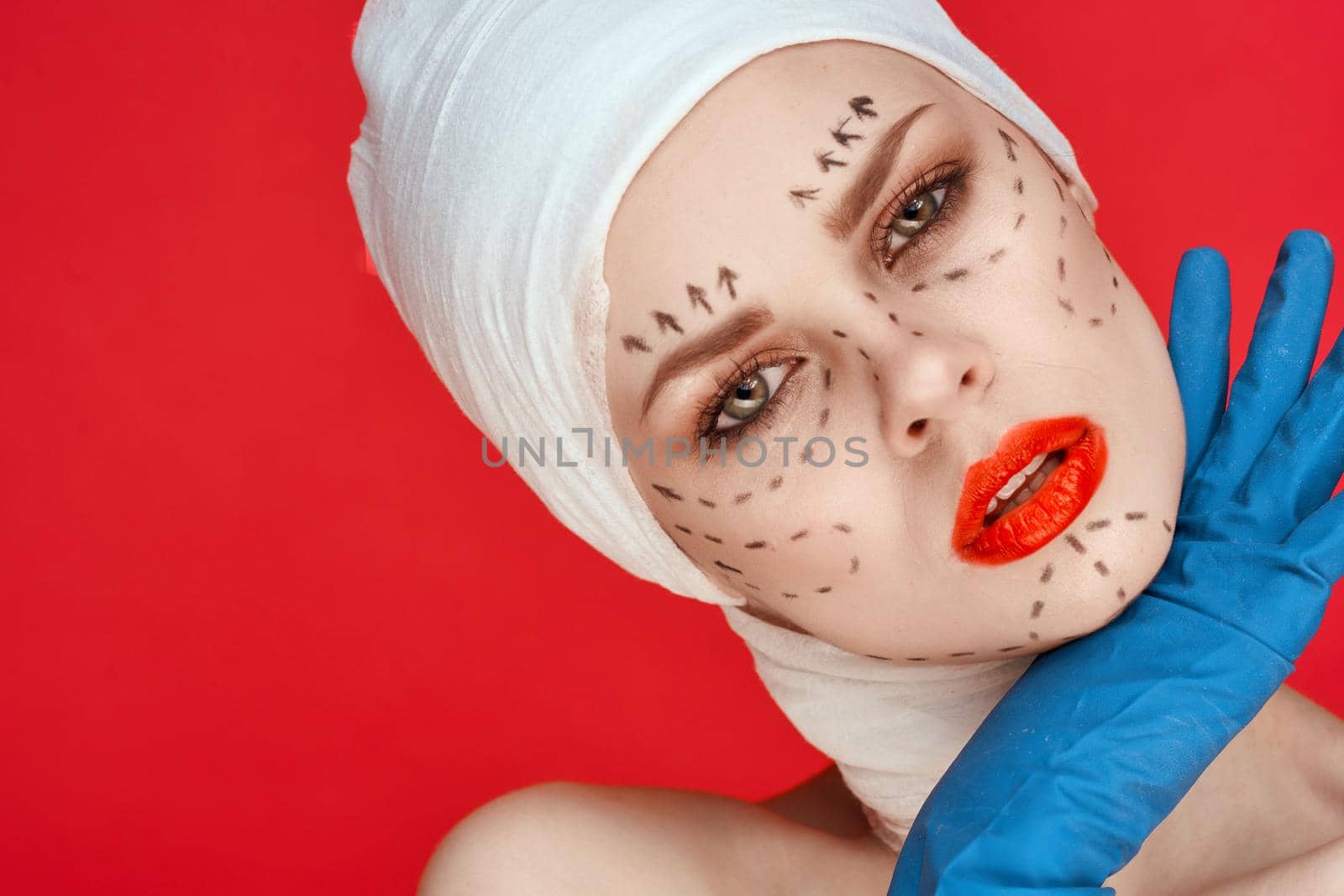 beautiful woman in blue gloves syringe in hands contour on the face lifting red background. High quality photo