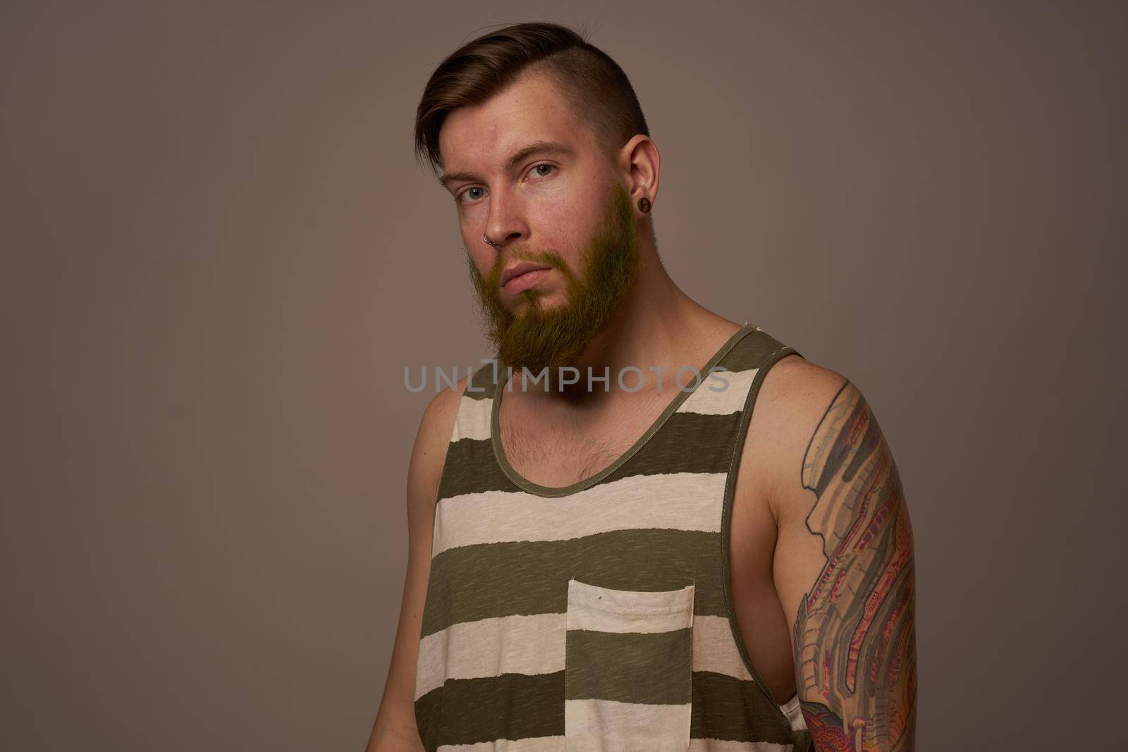 fashionable man with tattoos on his arms stylish hairstyle self-confidence studio. High quality photo