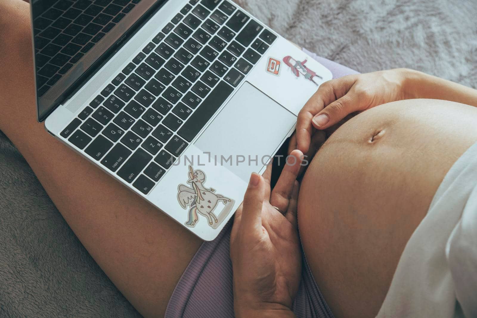 Pregnant caucasian woman working at laptop at home remotely, people using laptop for working at home, view from the top.
